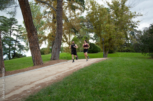 young caucasian man and woman couple running and talking on a sandy path in the park