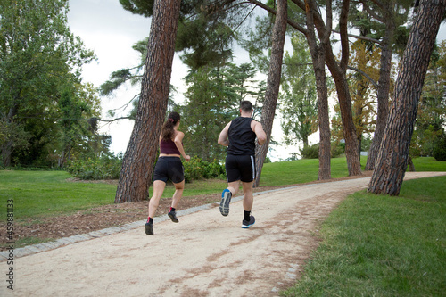 young caucasian man and woman couple running on a sandy path in the park