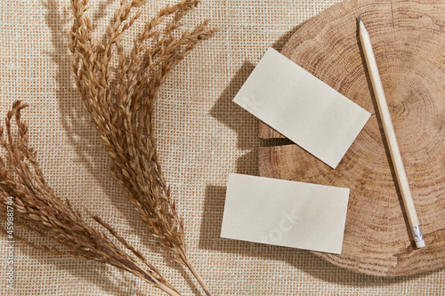 Flat lay of creative composition with mock up visit cards, wood, textile, natural materials, dry plants and personal accessories. Neutral colors, top view, template. photo