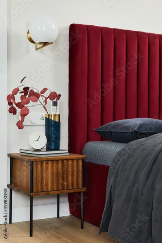 Minimalistic bedroom interior with red bed, grey bedclothes and wooden furniture. Glamour style inspiration. Template. photo