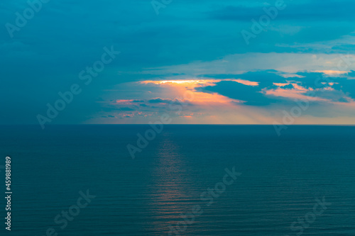 Sunset on the sea on a cloudy rainy day, sunlight on the dark surface of the sea