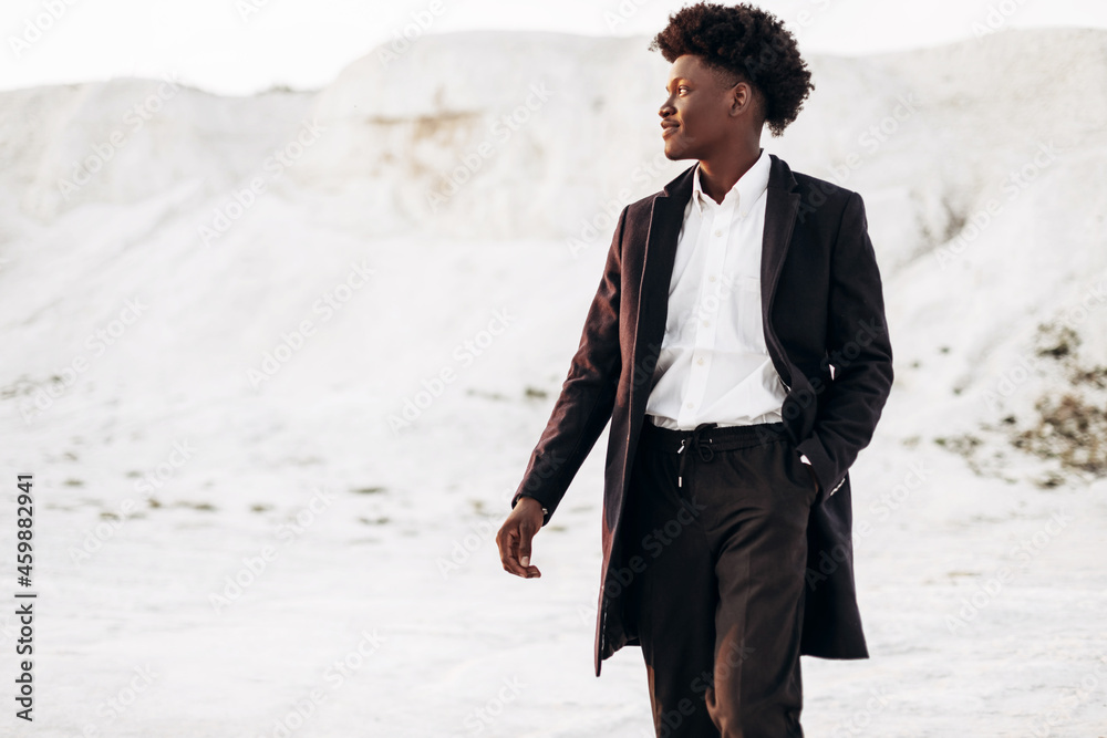 Stylish African American, fashionable black man in a suit, against the backdrop of rocky mountains Stylish African American, fashionable black man in a suit, against the backdrop of rocky mountains