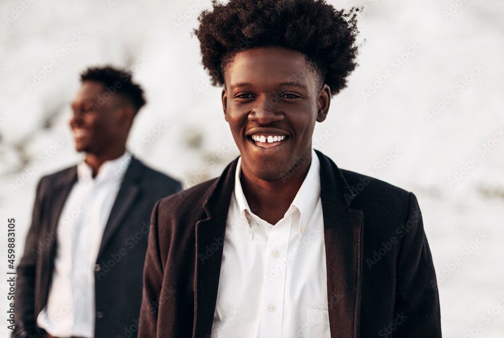 Two fashion models posing on the street, in classic clothes, fashionable African men, against the backdrop of rocks Two fashion models posing on the street, in classic clothes, fashionable African men, against the backdrop of rocks