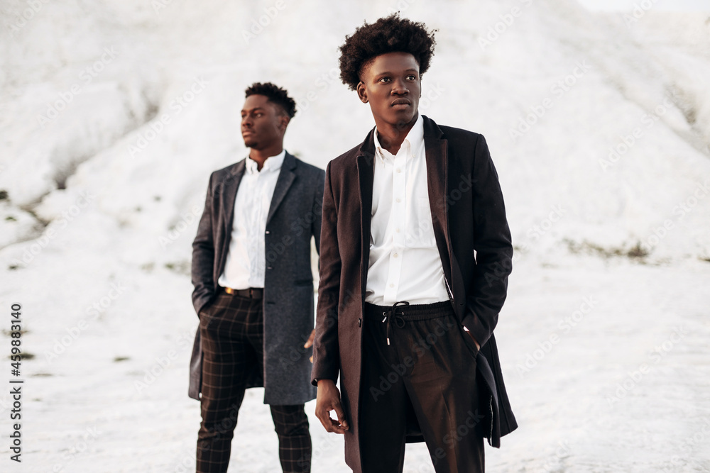 Two fashion models posing on the street, in classic clothes, fashionable African men, against the backdrop of rocks Two fashion models posing on the street, in classic clothes, fashionable African men, against the backdrop of rocks