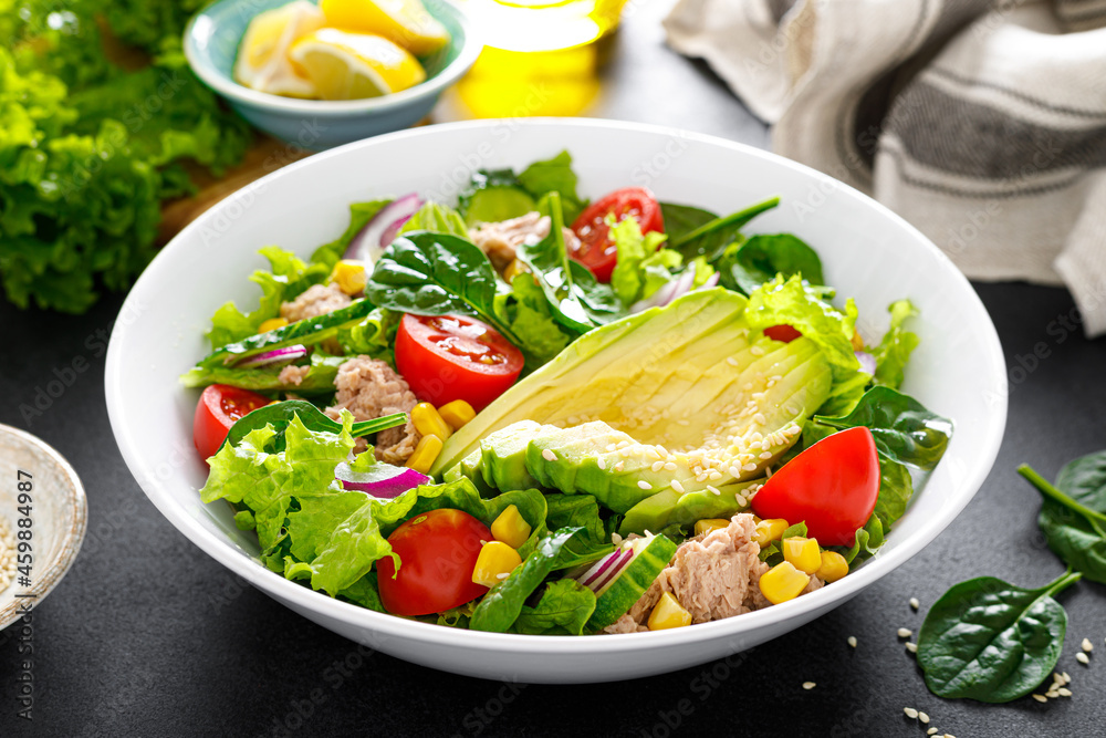 Avocado and tuna fresh vegetable salad with tomato, cucumber corn, onion, lettuce and spinach. Healthy and detox food concept. Ketogenic diet. Buddha bowl dish on black background. Avocado and tuna fresh vegetable salad with tomato, cucumber corn, onion, lettuce and spinach. Healthy and detox food concept. Ketogenic diet. Buddha bowl dish on black background.