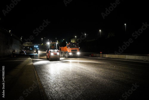 Road constructing at night, road roller and dump truck.