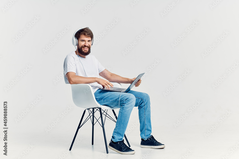 young man sitting on a chair with a laptop in headphones entertainment young man sitting on a chair with a laptop in headphones entertainment