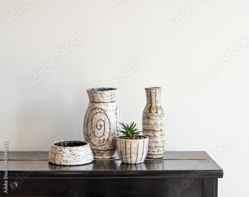 Mid-century modern pottery, grey vases and pots on a black furniture isolated