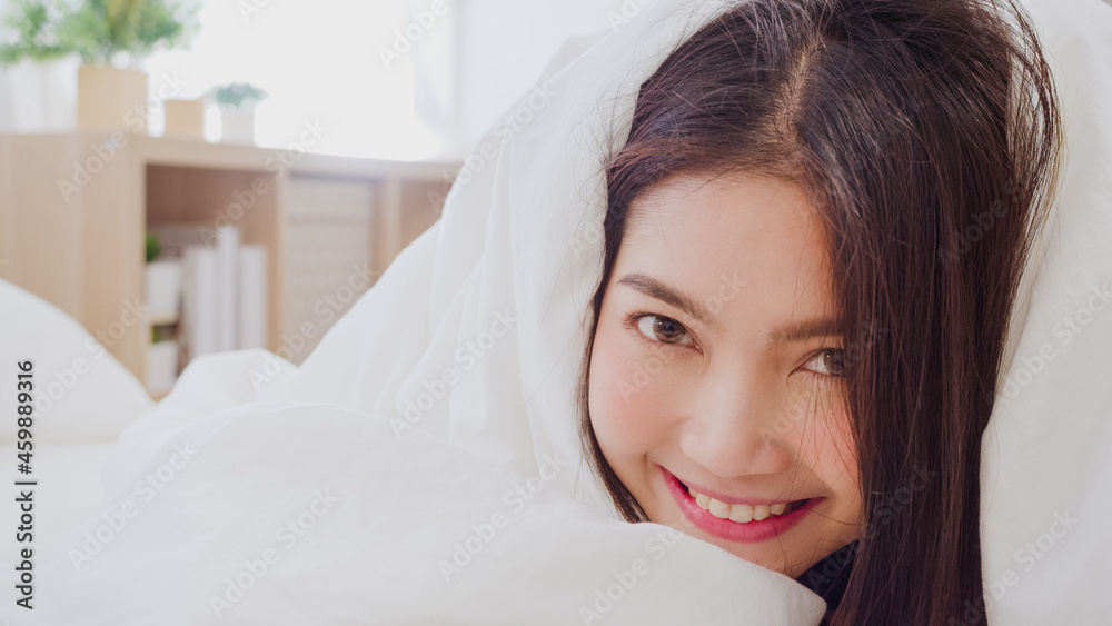 Asian woman smiling lying on bed in bedroom, Beautiful japanese female using relax time after wake up at home. Lifestyle women using relax time at home concept. Asian woman smiling lying on bed in bedroom, Beautiful japanese female using relax time after wake up at home. Lifestyle women using relax time at home concept.