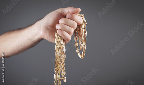 Male hand holding gold jewelry.