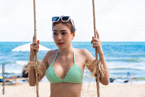 Happy asian woman in bikini relaxing on swing. Vacation concept. © ic36006