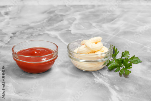 Glass bowls with ketchup and cheese sauce on kitchen table.