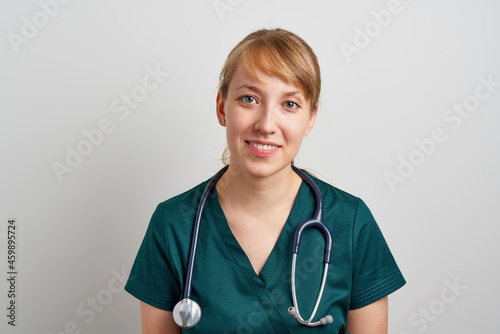 Smiling young female expert trustworthy nursing assistant with phonendoscope in green uniform. Healthcare worker in clinic. Portrait of professional paramedic. Horizontal of family resident physician