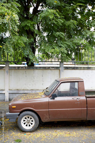 Old cars on the street and a wall overgrown with plants in Thailand © lichaoshu