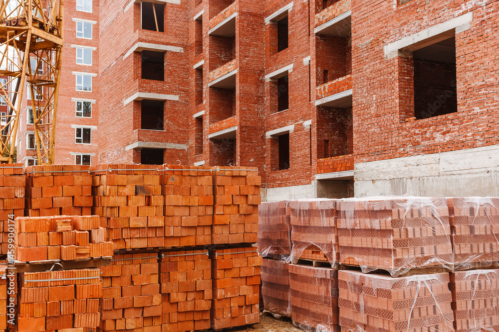 Bricks on a pallet on a construction site on a background of a brick structure Bricks on a pallet on a construction site on a background of a brick structure