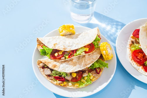 corn tortilla stuffed with meat and vegetables on a blue background. Taco