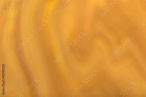 Blurred dark orange and golden background with wavy pattern. Defocused art abstract ocher gradient backdrop