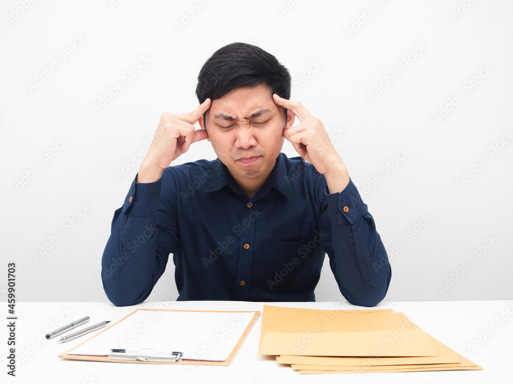 Asian man feeling headache with his work many document on the table Asian man feeling headache with his work many document on the table