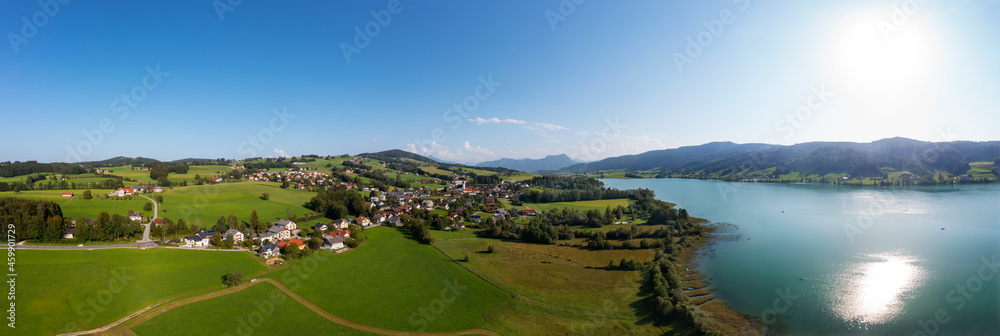 Austria, Upper Austria, Zell am Moos, Drone panorama of village on shore of Irrsee lake in summer Austria, Upper Austria, Zell am Moos, Drone panorama of village on shore of Irrsee lake in summer