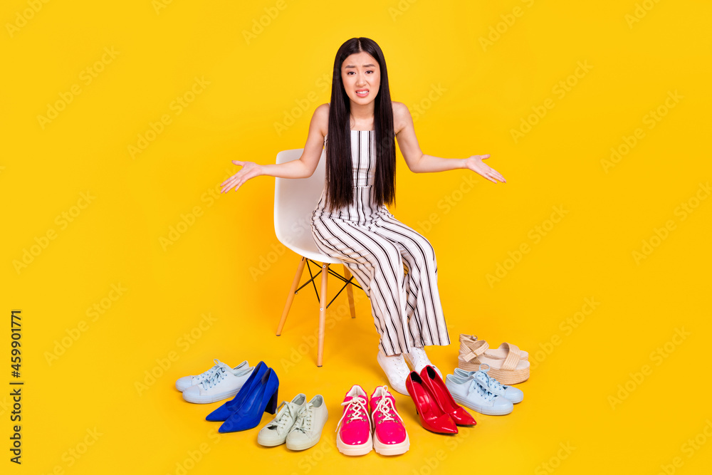 Full length body size photo girl irritated choosing shoes in fitting room unhappy isolated vivid yellow color background