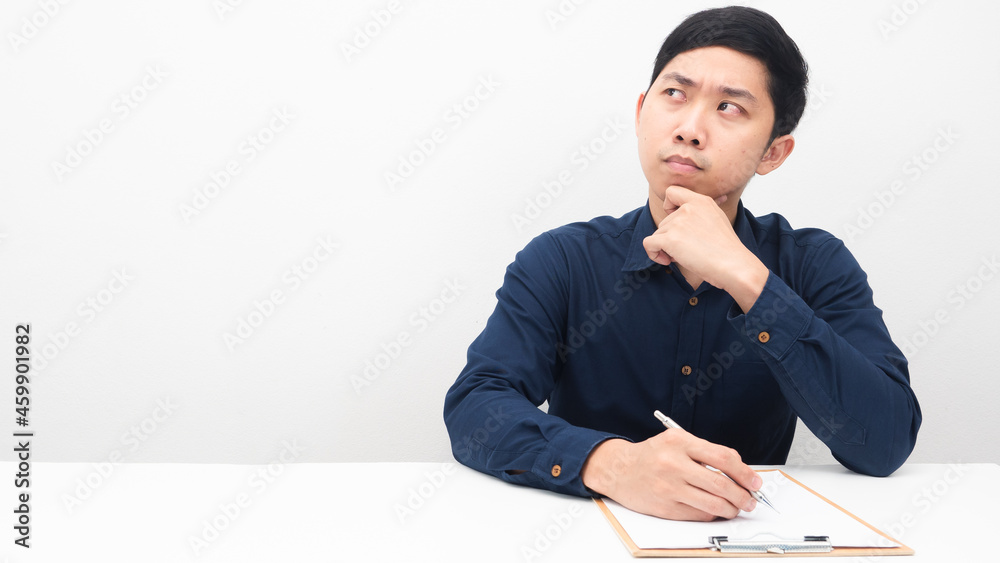 Asian man with document on the table thinking and looking at copy space Asian man with document on the table thinking and looking at copy space
