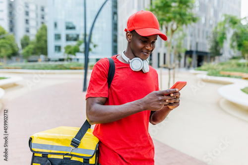 Delivery man wearing backpack text messaging through mobile phone