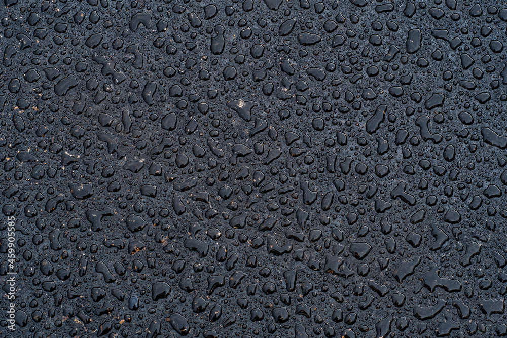 Dark background with large water droplets on newly paved asphalt. Road surface wet from rain after repair work. Dark background with large water droplets on newly paved asphalt. Road surface wet from rain after repair work.