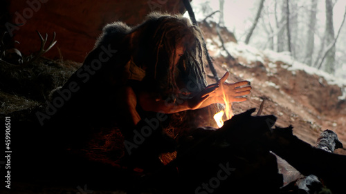Tableau sur toile Prehistoric caveman in cave sitting by fire