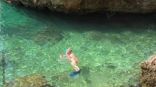 Woman in bikini, snorkeling in Punta Rata waterfront in Croatia around the famous Brela stone or Kamen Brela. Swimming in Croatian Adriatic Sea in the Split-Dalmatia County, close to Makarska. photo