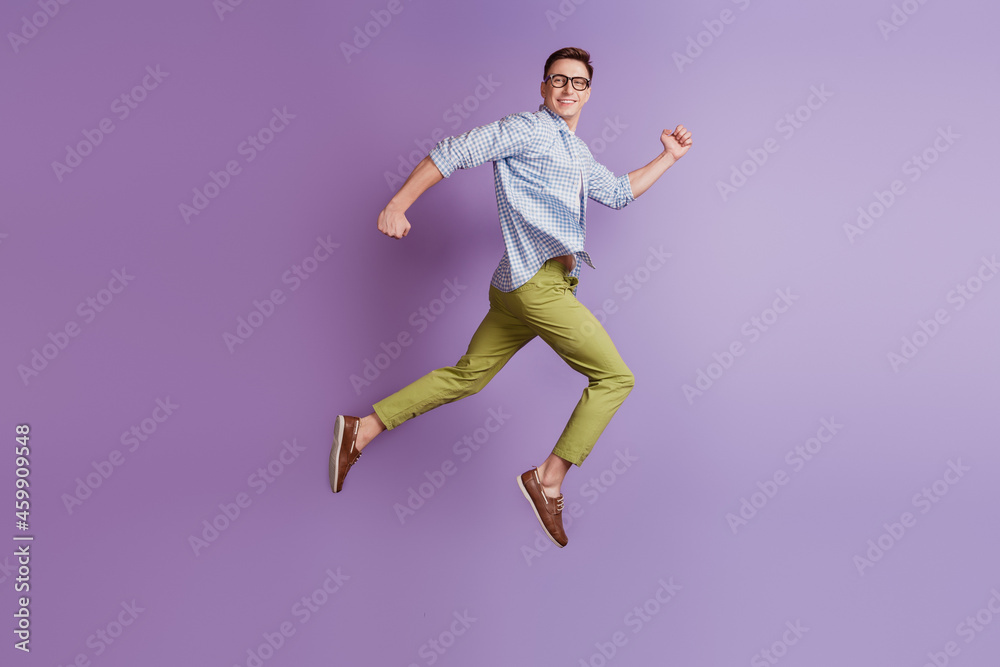 Portrait of jumper energetic active guy jump run look back empty space on violet background