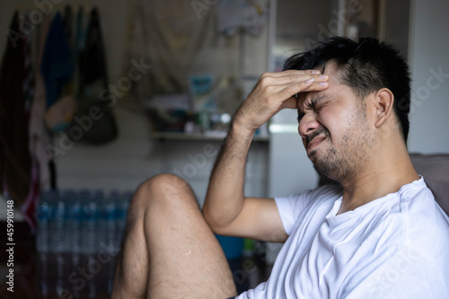 Asian male having migraine headache in the room at home