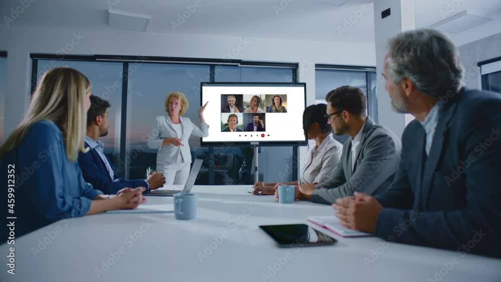 Woman standing at screen showing conference video call. Presentation of new technology to managers. Modern open space office interior. Woman standing at screen showing conference video call. Presentation of new technology to managers. Modern open space office interior.