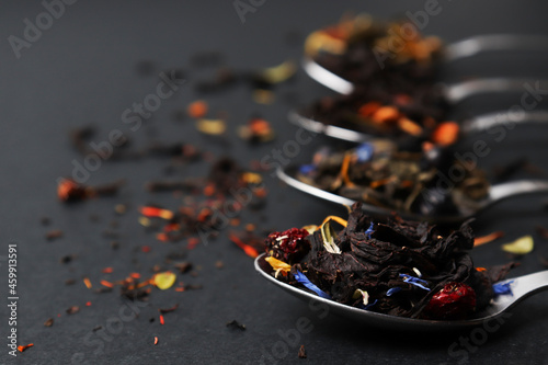 Dried Tea Leaves in a teaspoon. Assortment of bright tea on a dark table, composition with different types of tea. The concept of tea. Tea leaves, copy spase