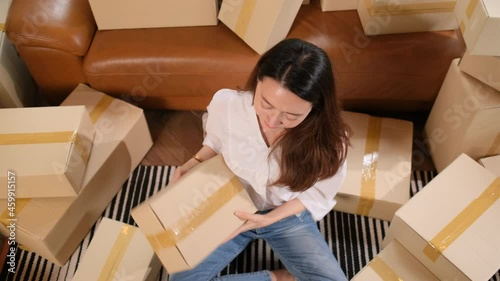 Top view of young Asian woman sit on floor then receive box or carton and look at camera and smiling.