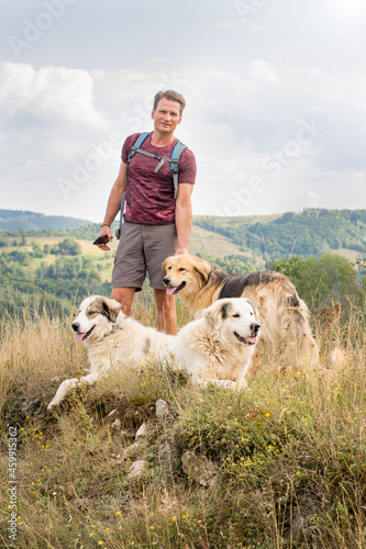 Adult man hiking in nature with shepherd dogs, on the hills in s photo