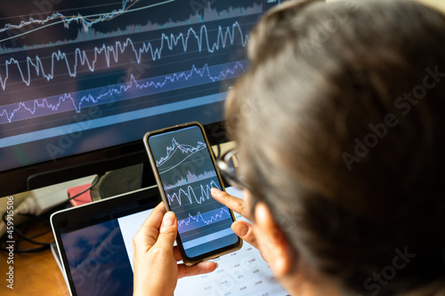 Woman investing in stock market and using technology to compare charts photo