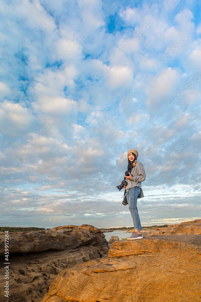 A backpacker woman stands on the rock pit of the Grand Canyon at sunset at three thousand waves. A backpacker woman stands on the rock pit of the Grand Canyon at sunset at three thousand waves.