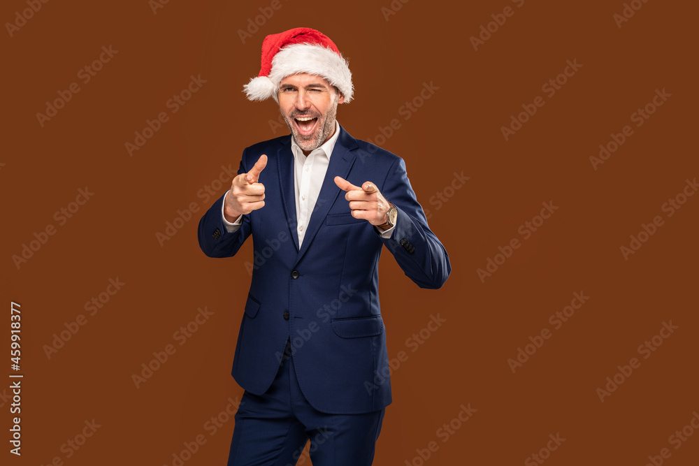 Happy handsome businessman wearing santa claus cap pointing his fingers to the camera Happy handsome businessman wearing santa claus cap pointing his fingers to the camera