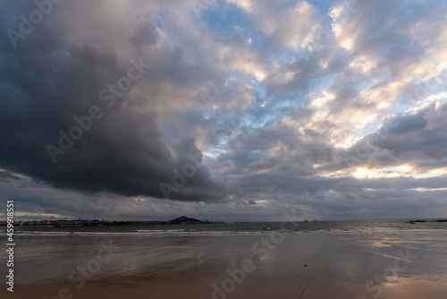 The sky is covered with dark clouds and the beach is cloudy