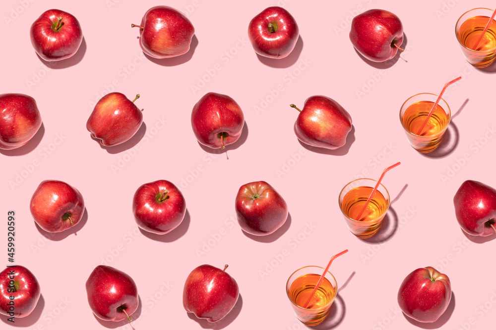 Red apples and juice on pink background. Pattern, top view, flat lay.