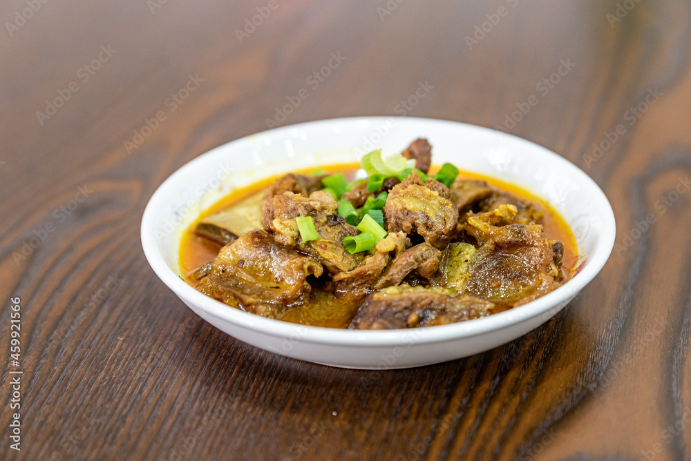 The beef dish is in the plate on the wooden table The beef dish is in the plate on the wooden table