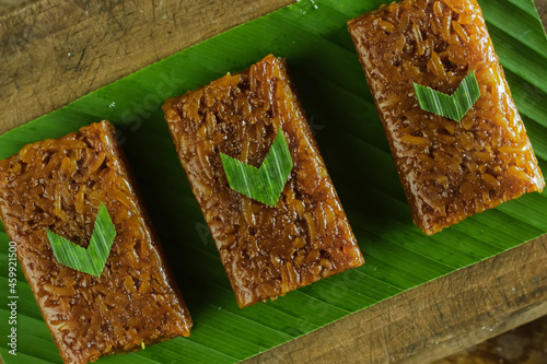 Wajik on wood background. Wajik is traditional snack made with steamed glutinous (sticky) rice and further cooked in palm sugar, coconut milk, and pandan leaves. photo