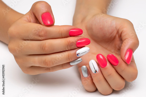 Hot pink  white  silver manicure  with silver stripes and crystals on the nameless nails. Short oval nails. Close-up on a white background.