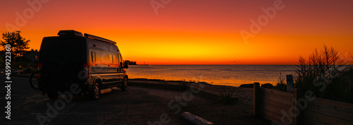 Good Morning Cape Cod. Red and orange colored sunrise at the beach with the view of a mobile home park.