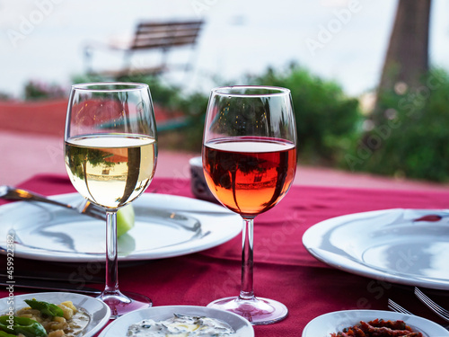 wine in a restaurant. Two Glasses of white and rose Wine on the table of a restaurant, Alcoholic drink on a served set table on a background of the Beach. Transparent wine on the summer terrace 