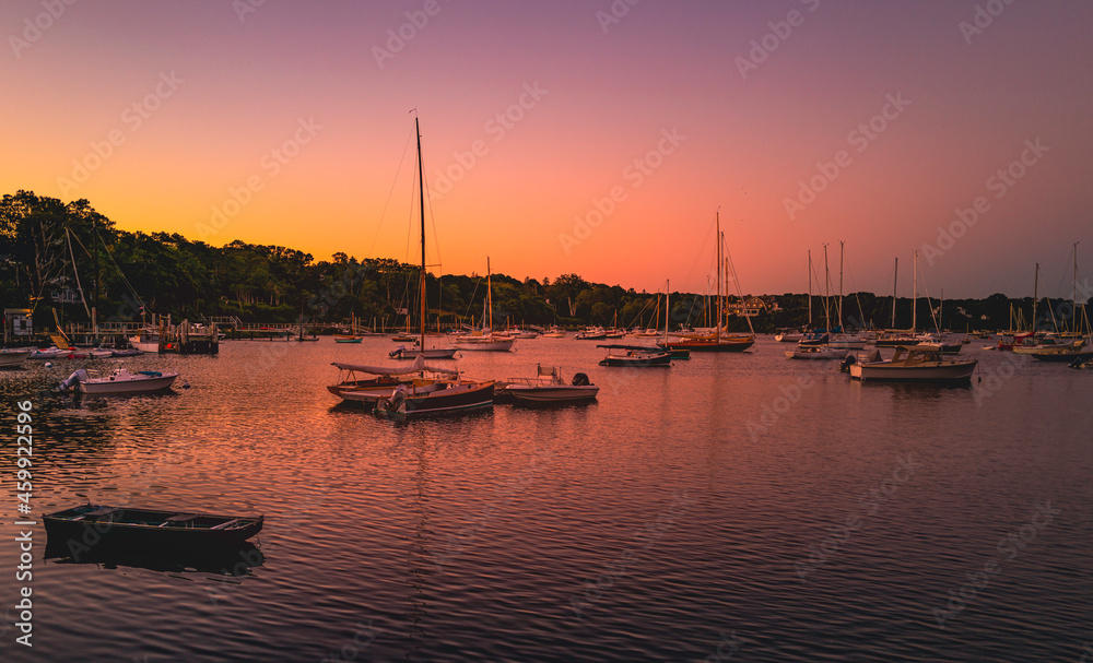 Pink sunrise at the marina with moored boats and yachts on Cape Cod in autumn