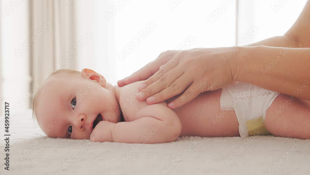 Mother doing massage on her healthy infant baby. Small caucasian newborn laying on his belly while his mother is performing a massage for his small back and developing muscles. . Mother doing massage on her healthy infant baby. Small caucasian newborn laying on his belly while his mother is performing a massage for his small back and developing muscles. .