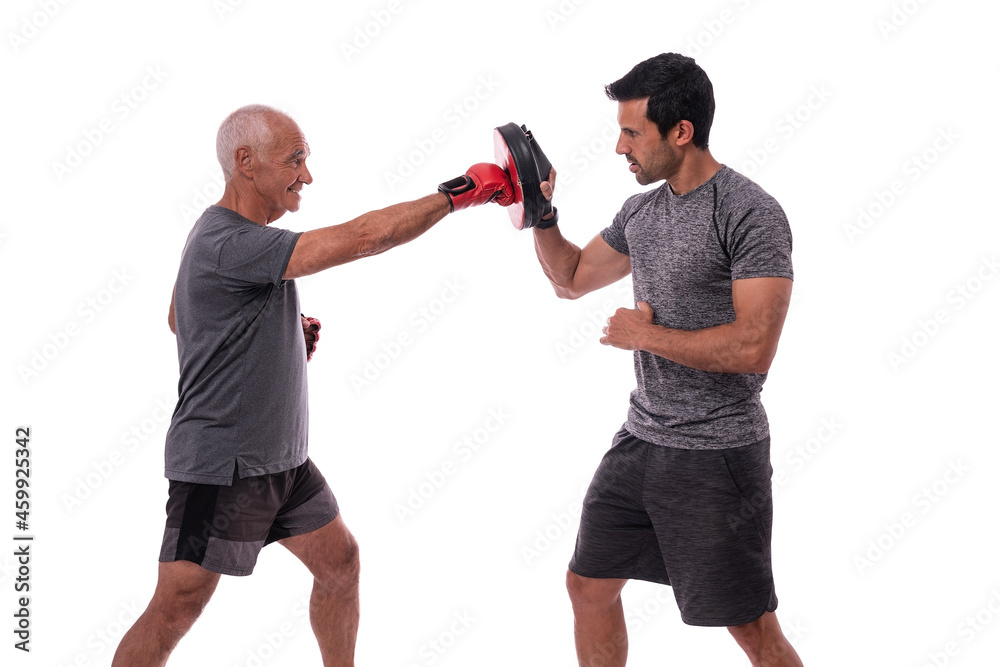 Elderly man hits with boxing glove in defense, personal fitness trainer, concept of working together. On white background. Elderly man hits with boxing glove in defense, personal fitness trainer, concept of working together. On white background.