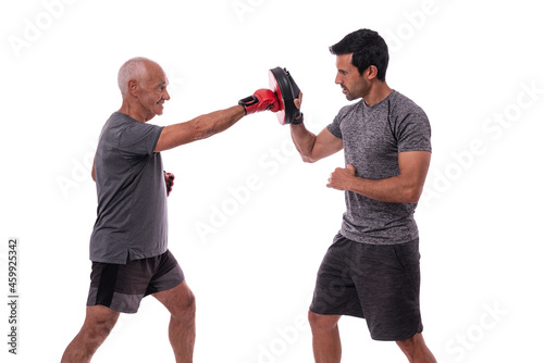 Elderly man hits with boxing glove in defense, personal fitness trainer, concept of working together. On white background.