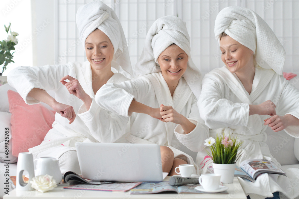 Young women in bathrobes with laptop at home Young women in bathrobes with laptop at home